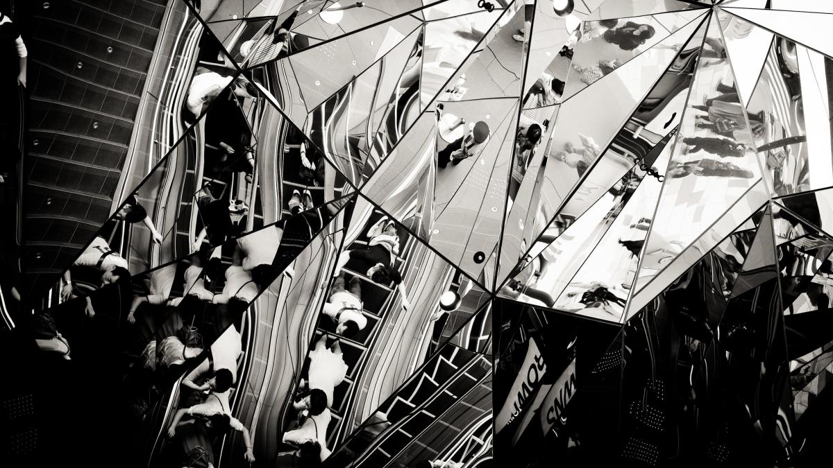 Black and white photo of people in a subway station through multiple reflections