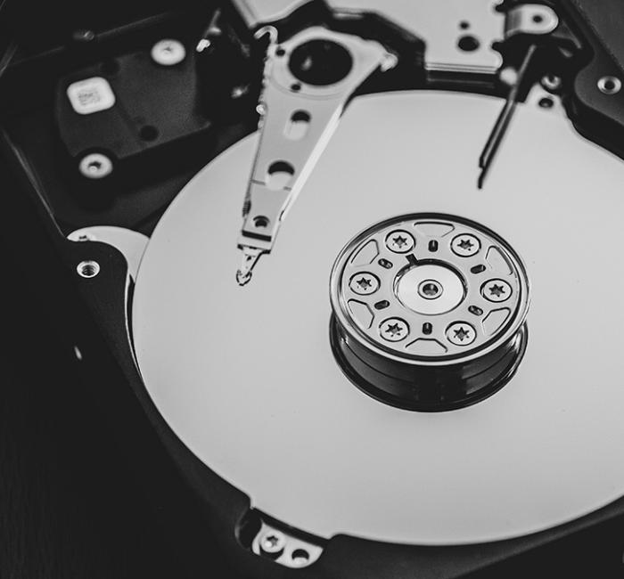 A close-up view of the inside of a hard disk drive, revealing the magnetic platters used for data storage and the mechanical arm with the read/write head.