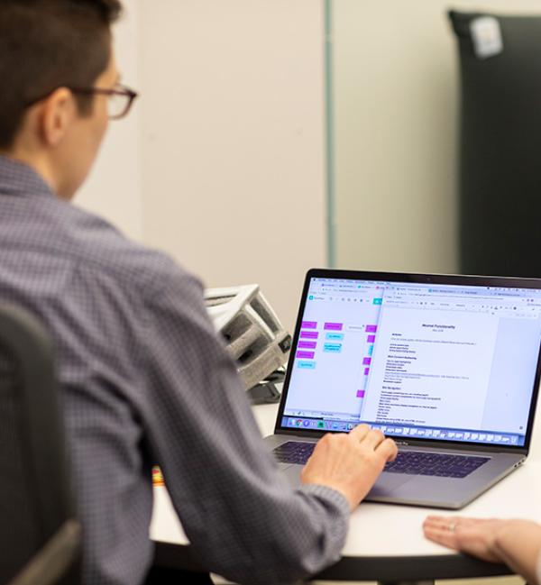 Person sitting at a table working on a laptop.