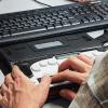 A person using a braille keyboard at a workstation